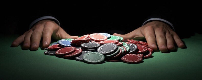 a close-up of a poker table with many poker chips between two hands